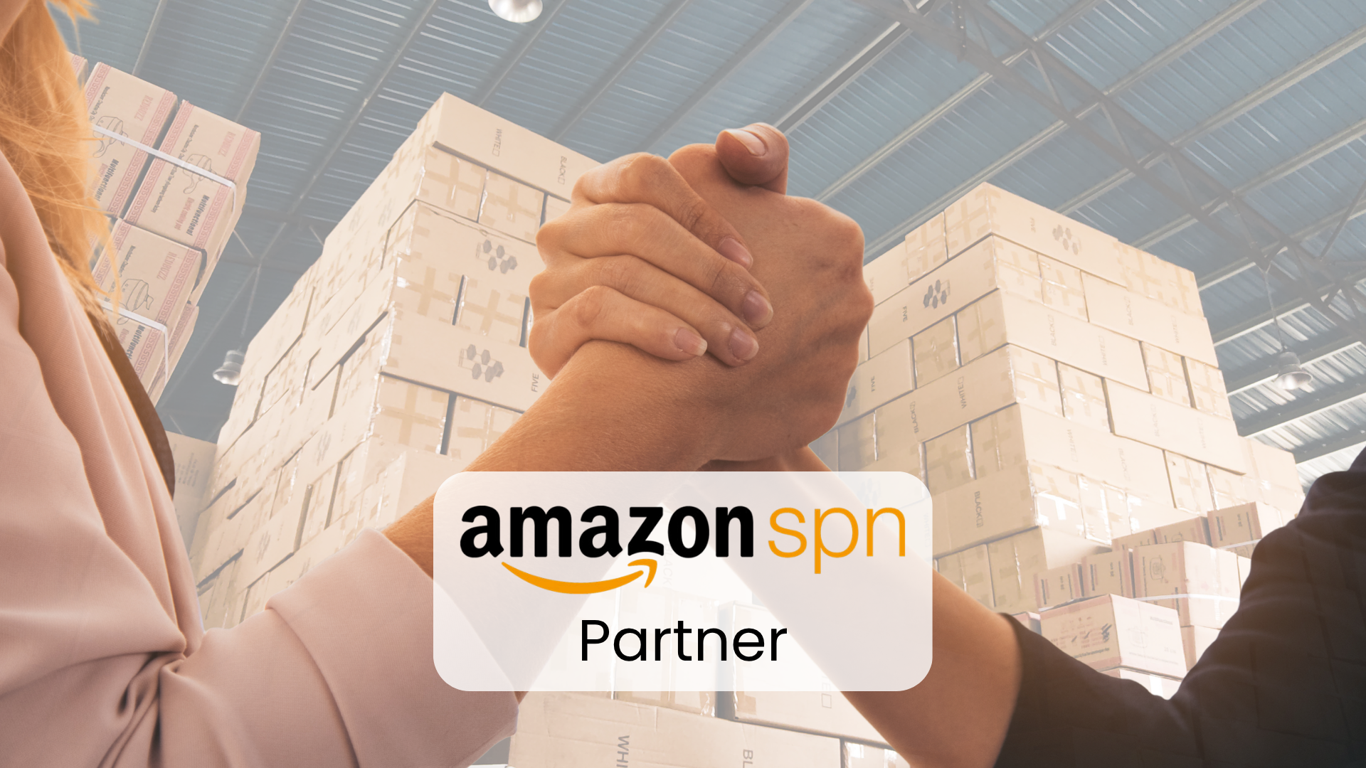 Dwie splecione dłonie na tle magazynu pełnego kartonów, na pierwszym planie napis Amazon SPN Partner