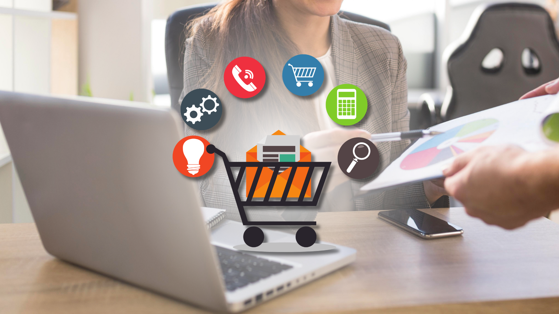 Kobieta przy laptopie omawia wykres kołowy z rozmówcą, nad biurkiem ikony e-commerce – rekrutacja E-commerce Managera
